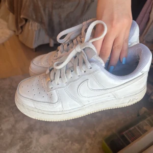 Vita Nike Air Force 1 sneakers  - Säljer ett par klassiska vita Nike Air Force sneakers. De är sparsamt använda, hållt sig väldigt vita och har inga större defekter än vad man ser på sista bilden. I storlek 36 men skulle säga att dem passar folk med 37 också☺️