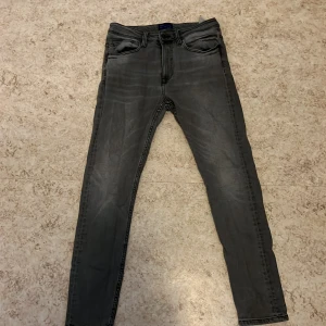 Grå jeans från Zara Man - Snygga grå jeans från Zara Man i en klassisk straight fit. Perfekta för en stilren look med fem fickor och knappgylf. Tillverkade i ett slitstarkt material som passar både till vardags och mer uppklädda tillfällen.
