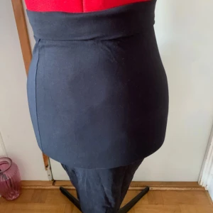 Svart kjol från 157 - Snygg svart kjol från 157 med hög midja. Perfekt för en stilren look. Kjolen är enkel och elegant, vilket gör den lätt att matcha med olika toppar.