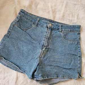 Blå jeansshorts - Säljer ett par klassiska blå jeansshorts med normal passform. Shortsen har en knapp och dragkedja framtill samt bälteshällor. Perfekta för sommardagar!