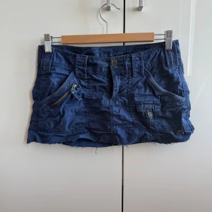 Viral 2000s blå minikjol med fickor!! - Snygg blå kortkjol med flera fickor och knappdetaljer. Kjolen har en dragkedja och bälteshällor för extra stil. Skit snygg för en sommar outfit!!