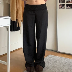 Svarta kostymbyxor med spetsdetalj - Snygga svarta byxor med en bred spetsdetalj vid midjan. Byxorna har en loose passform och är perfekta för en stilren look. De är lågmidjade och tillverkade i ett mjukt material som ger en bekväm känsla. Helt ny med prislappen kvar❤️❤️ Ordinarie pris 600 kr men säljer för 350kr❤️❤️