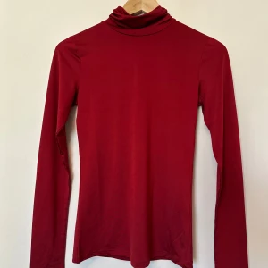 Röd polotröja från Lindex - Snygg röd polotröja från Lindex i satin. Perfekt för kyligare dagar med sin långa ärmar och klassiska polokrage. En stilren baströja som passar till mycket.