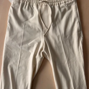 Nya beiga byxor från Zara - Säljer här ett par helt nya beige byxor från Zara med elastisk midja och snörning. Kvittot är borttappat men lappen sitter kvar. Byxorna har en rak passform och en liten bakficka. De är lite mer avslappnade i känslan, men ger en helt annan känsla utåt. Helt enkelt perfekt när man vill klä upp sig men vill ha det skönt. 