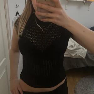 Svart mönstrad topp från Zara - Snygg svart stickad topp från Zara med korta ärmar och ett diskret mönster. Perfekt för en stilren look. Toppen har en rund halsringning och är tillverkad i ett bekvämt material.