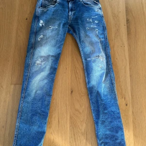 Blå jeans från Replay - Tjena! Säljer ett par snygga blå jeans från Replay med slitna detaljer och en klassisk femficksdesign. Det är modellen ambass. Jeansen har en knappgylf och är perfekta för en avslappnad stil. Det är 34 i längd 