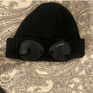  C.P. Company mössa - Snygg svart ribbad mössa från C.P. Company  Perfekt för att ge din outfit en unik touch. Mössan är både stilren och funktionell. PRIS KAN DISKUTERAS!