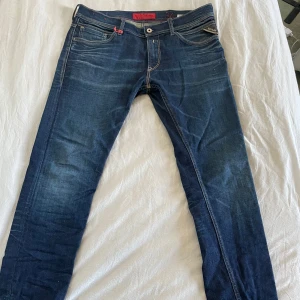 Blå jeans från Replay - Snygga blå jeans från Replay med klassisk femficksdesign och kontrastsömmar. Jeansen har en tight passform och är perfekta för en avslappnad stil. Märkeslappen i rött ger en cool detalj. Sitter riktigt tight och passar därför lite mindre storlekar också. Är ett par äldre replay jeans men har bevarats i okej skick. 