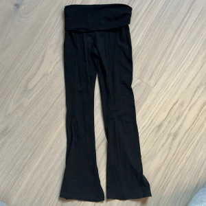 Svarta bootcut leggings från Gina Tricot - Svarta leggings från Gina Tricot med bootcut-modell och hög midja. Mjukt och stretchigt material som sitter skönt på kroppen. Perfekta för en avslappnad och trendig look.