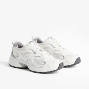 Vita sneakers - Snygga vita sneakers med grå/silver detaljer. Skorna har snörning och en tjock, sportig sula som ger en modern look. Köpte på hm, används 1 gång, storlek 40 & köpts för 399kr