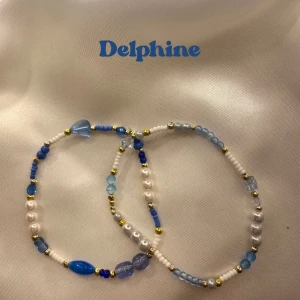 Delphine bracelet - 2 pack - Två elastiska armband med mix av blå, vita och guldiga pärlor i olika former och storlekar. 