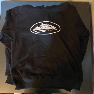 Svart Cortiez Hoodie - Svart sweatshirt med vitt tryck av Alcatraz på bröstet. Tröjan har rund hals och långa ärmar. Mjuk och bekväm, perfekt för dig som gillar streetwear och unika motiv. Denna hoodie är oanvänd där jag köpte för stor storlek. 