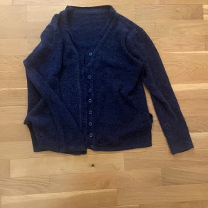 Mörkblå kofta med knappar - Mysig mörkblå kofta knäppning framtill. Långärmad och i ett mjukt, stickat material som passar perfekt till vardags. Enkel och stilren design som är lätt att matcha.