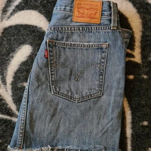 Snygg jeanskjol från Levi's! - Säljer en klassisk blå jeanskjol från Levi's med rå kant nertill och femficksmodell. Kjolen har knapp och dragkedja framtill samt tydliga sömmar och Levi's-logga på bakfickan. Supersnygg.