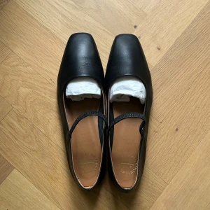 Svarta ballerinaskor från ATP Atelier - Stilrena svarta ballerinaskor från ATP Atelier med fyrkantig tå och tunn rem över foten. Skorna är tillverkade i skinn och har en låg klack samt platt sula. Endast använda vid ett tillfälle - helt felfria och i nyskick, skokartong, emballage och dustbag kommer med! Omsulade hos skomakare för att inte vara hala och kunna användas utomhus. Säljer pga fel storlek. Nypris ligger på 3500kr