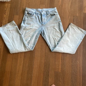 Ljusblå jeansbyxor från Bridle - Säljer ett par Tvär Feta ljusblå jeansbyxor från Bridle med klassisk femficksdesign och raka ben. Jeansen har normal passform och är tillverkade i denim med subtila slitningar för en avslappnad look. Perfekta för dig som gillar en tidlös stil.