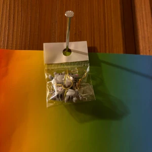 Grå katt örhängen  - Säljer ett par söta örhängen med små grå katter i plast och guldfärgade krokar. Perfekta för dig som vill ha något lekfullt och unikt i din stil. Kommer i en liten plastpåse.