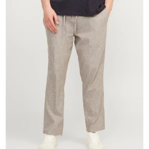 Beige/grå linnebyxor - Säljer ett par beige/gråa linnebyxor med elastisk midja och rak passform. Byxorna har en enkel och stilren look, perfekta för varma dagar. Lätta och luftiga med fickor fram och bak. Passar dig som gillar en avslappnad och trendig stil.