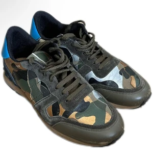 Valentino Rockrunner sneakers med camouflage - Snygga Valentino Rockrunner sneakers med camouflage-mönster i grönt, brunt och svart. Skorna har blå detalj på hälen, svarta snören och paneler i mocka och skinn. Perfekta för dig som vill sticka ut med en unik stil. Skicket är 8,5/10, säljer för 1699. Ställ gärna frågor om det är något du undrar😊