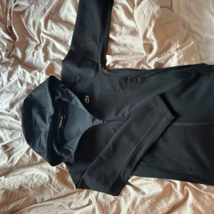 Svart sportig hoodie från Lacoste Sport - Säljer en svart hoodie från Lacoste Sport med dragkedja och huva. Tröjan har det klassiska Lacoste-märket på bröstet och är tillverkad i ett syntetmaterial som passar perfekt till träning eller en aktiv vardag. Jag har inte använt den någon gång då jag fick den på min födelsedag men den var för liten. Den är beställd från Zalando och kunde inte returnera den för jag tog av etiketten. Org pris: 1300