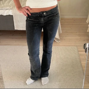 Svarta lågmidjade jeansbyxor med dragkedjedetaljer - Säljer ett par svarta jeans med låg midja och bootcut. Jätte snygga detaljer och har använts sparsamt! Helt slutsålda🥰köp direkt