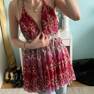 Röd- och vitmönstrad halterneck blus - Säljer en luftig och somrig halterneck blus med röd och vit geometrisk mönstring. Toppen har knyt i nacken och markerad midja med volangig nederdel. Perfekt till varma dagar och enkel att styla med jeans eller kjol.