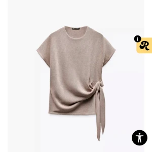 Zara topp med knut - Säljer en beige topp med rund halsringning och korta ärmar. Toppen har ett snyggt knytband i sidan som ger en trendig look. Perfekt att styla med matchande byxor eller jeans. Använd fåtal gånger.