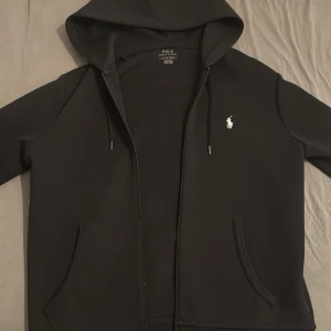 Svart hoodie från Polo Ralph Lauren - Säljer nu denna Ralph lauren zip hoodie i oerhört bra skick, nästan som ny, på grund av att den inte passar mig längre, rekommenderar denna för folk som bär storlek S. Den är såklart äkta och köptes för 1800 från cettire med transaktionen som bevis. Vid fler frågor tveka inte att kontakta mig!
