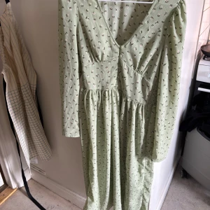 Ljusgrön blommig långklänning från monki Monki - Säljer en ljusgrön långklänning från Monki i storlek 32. Klänningen har små blommor, slits, v-ringning och långa ärmar.