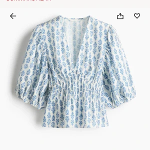 Vit och blå blus med puffärm och v-ringning - Säljer en söt vit klänning med blått blommigt mönster. Klänningen har v-ringning, smockad midja och puffiga trekvartsärmar. Perfekt för sommarens alla tillfällen. Lätt och luftig känsla.