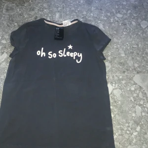 Svart t-shirt med tryck från H&M - Svart t-shirt från H&M med texten 'oh so sleepy' i vitt tryck framtill. Klassisk rund halsringning och korta ärmar. Perfekt för en avslappnad stil.
