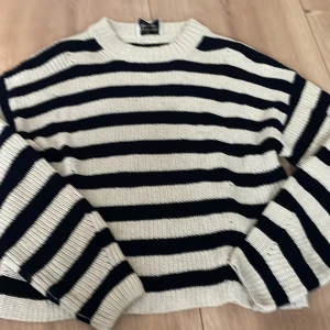 Randig stickad tröja från Les Coyotes de Paris - Säljer en snygg stickad tröja från Les Coyotes de Paris med svarta och vita horisontella ränder. Tröjan har rund halsringning och långa ärmar. Perfekt för en trendig och avslappnad look.