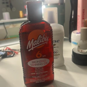 Malibu Bronzing Tanning Oil SPF 6 - Bronzing tanning oil med SPF 6 från Malibu. Ger en tropisk kokosdoft och är vattenresistent. Oljan är i en röd plastflaska med orange sol-logga och är avsedd för att ge huden en solkysst look.  Super härlig!