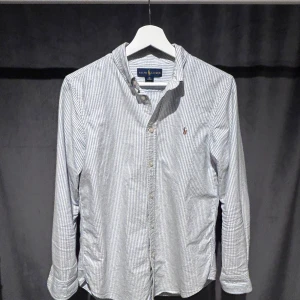 Ralph Lauren Skjorta - Klassisk långärmad skjorta från Ralph Lauren i vitt och blått med tunna ränder. Skjortan har knappar framtill och en broderad logga på bröstet. Storlek  Xs. Skriv vid minsta fundering! 