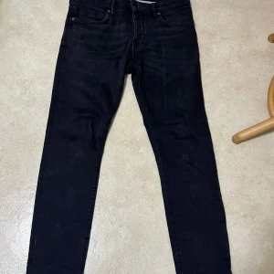 Svarta jeansbyxor herr - Säljer ett par mörkgrå/svarta  jeansbyxor från Neuw i klassisk straight modell. Byxorna har fem fickor, dragkedja och knapp i midjan. Passar dig som vill ha en enkel och stilren look. Midjemått W30 och längd L32.