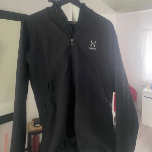 Svart vindjacka från Haglöfs - Säljer en svart vindjacka från Haglöfs i herrstorlek L. Jackan har dragkedja framtill, hög krage och två sidofickor med dragkedja. Perfekt för utomhusaktiviteter och enkel att matcha med det mesta.