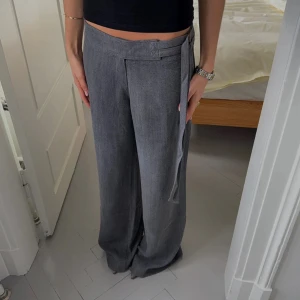 Grå byxor med bältesdetalj - Säljer mina jättefina lågmidjade byxor från design by si då de tyvärr är för små. De har en bältes detalj i midjan som gör att det går att justera storleken ganska bra själv. De är endast använda två gånger. Nypris är 650 kr. Midjemått: 38 cm (men går att gör mindre). Innerbenslängd: 78 cm. PRISET KAN DISKUTERAS VID SNABB AFFÄR!💗💗