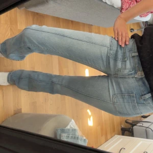 Ljusblå lågmidjade bootcut jeans från Madlady - Säljer ett par ljusblå bootcut jeans från Madlady med snygga framfickor och dubbla knappar i midjan. Jeansen har en klassisk bootcut-passform. Perfekta för dig som gillar en retro vibe och vill ha något som sticker ut.