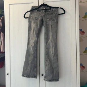 Grå bootcut jeans med fickor - Snygga grå Jeans med bootcut-ben och markerade sömmar framtill. Jeansen har två fickor fram och bak samt dubbla silverfärgade knappar i midjan. Perfekta för dig som gillar en retro vibe, använda men kan användas mkt mer 