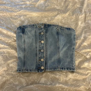 Jeans tubtopp från Pull&Bear - Säljer en snygg ljusblå jeans tubtopp från Pull&Bear i storlek M med knappar fram, är i väldigt gott skick.💓