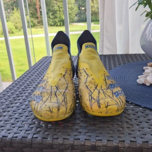 Adidas Predator Wolverine fotbollsskor - Unika Adidas Predator Demonskin fotbollsskor i Wolverine/X-men edition. Skorna har en cool gul och blå design med svarta detaljer och Wolverine-motiv på hälen. Tillverkade i syntetmaterial med struktur för extra grepp på bollen. Perfekta för dig som vill sticka ut på planen.