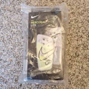 Helt nya Nike Mercurial Lite "CR7" benskydd - Säljer dessa helt nya aldrig använda och aldriga öppnade Nike Mercurial Lite "CR7" benskydd i storlek XL. Orginalbox och ett par benskyddsband ingår. Skick: 10/10