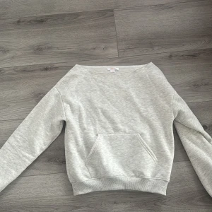 Ljusgrå sweatshirt från Gina Tricot - Enkel och stilren ljusgrå sweatshirt från Gina Tricot. Tröjan har lång ärm, rund halsringning och en stor magficka framtill. Perfekt för en chill look och passar till allt. Mjuk och skön i bomullsmix. använd en gång 