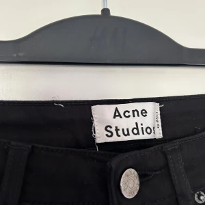 Svarta skinny jeans från Acne Studios - Säljer ett par svarta skinny jeans från Acne Studios med klassisk femficksdesign och silverfärgad knapp. Jeansen har hög midja. Perfekta för dig som gillar minimalistisk och stilren look. Modell Pin Black. Storlek 28/32. 