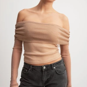 Glittrig offshoulder topp från NA-KD - Säljer en snygg glittrig beige offshoulder topp från NA-KD. Toppen har långärmade ärmar i meshliknande material och sitter tight över kroppen. Perfekt för dig som vill sticka ut med en elegant och trendig look.