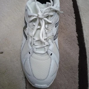 Vita New Balance sneakers med mesh - Snygga vita New Balance sneakers med svart logga på sidan. Ovandelen är i mesh och syntet för bra andningsförmåga. Grov sula med svart och vitt mönster ger grymt grepp. Klassisk snörning och sportig vibe, perfekta för dig som gillar streetstyle.storleken är 39,5