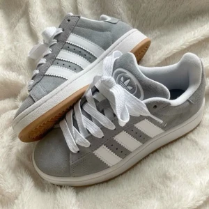 Grå Adidas Campus sneakers - Snygga Adidas Campus sneakers i grå mocka med klassiska vita ränder och vit sula. Knappast använda köpte för två veckor sen🥰