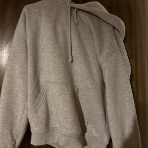 Grå hoodie med huva och magficka - En klassisk grå hoodie med huva och snörning samt en stor magficka framtill. 