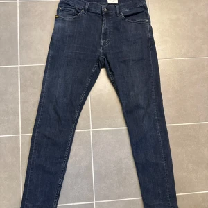 Mörkblå skinny jeans Tiger of Sweden 32/32 - Snygga mörkblå jeans från Tiger of Sweden med klassisk femficksdesign och smal passform. Jeansen har en stilren look med raka sömmar och diskreta detaljer, perfekta för dig som gillar en clean och modern stil. Materialet är mjukt och stretchigt jeans.