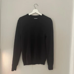 Mörkblå stickad tröja These Glory Days - En stilren mörk blå stickad merino ull tröja från These Glory Days. Tröjan har rund hals, långa ärmar och ribbade muddar vid hals, ärmslut och nederkant. Perfekt för dig som gillar enkel och clean look. Passar dig som vill ha en klassisk och tidlös vibe. Priss kan diskuteras!